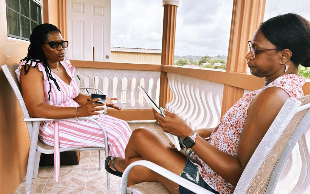 Two women sitting on a porch with their phones.